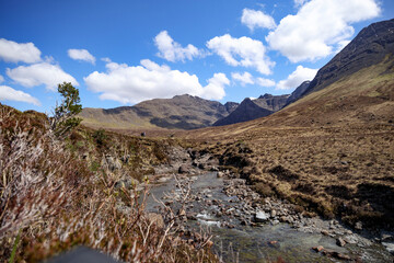 Stunning landscape of the Isle of Skye in Scotland showcasing a serene stream amidst dramatic mountain backdrops under a clear blue sky