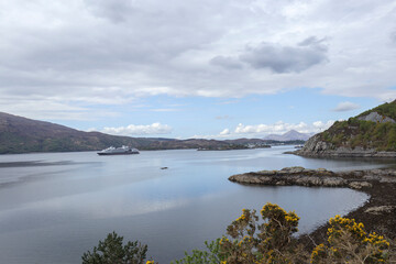 Majestic Scottish coastline showcasing serene waters and distant hills on a cloudy day