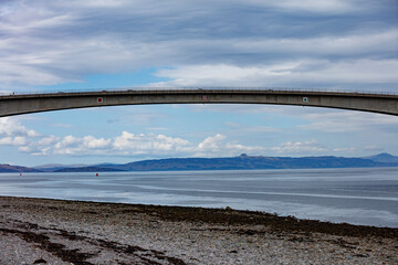 View of the Skye Bridge connecting the Isle of Skye to the mainland of Scotland with calm waters and cloudy skies above