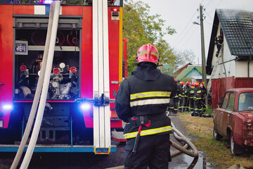 Firefighters responding to an emergency with their equipment in a suburban area during a rainy day
