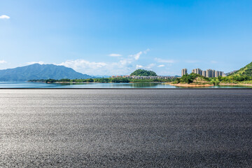 Asphalt road and blue lake with islands nature landscape under blue sky. Outdoor road background.
