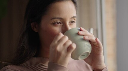 Thinking, window and coffee with woman in living room of house for morning routine, vision and idea. Relax, peace and memory with person and tea cup at home for wake up, inspiration and reflection
