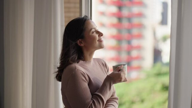 Thinking, window and coffee with woman in living room of house for morning routine, vision and idea. Relax, peace and memory with person and tea cup at home for wake up, inspiration and reflection

