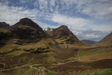 Stunning view of the rugged hills and mountains of Scotland under a dramatic sky with patches of snow in early spring