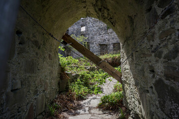 Obraz premium Exploring the ruins of Castle Tioram in the scenic Scottish Highlands through a stone archway overgrown with vegetation