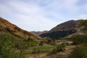 Naklejka premium Scenic view of the iconic bridge spanning a lush valley in the Scottish highlands under a clear sky