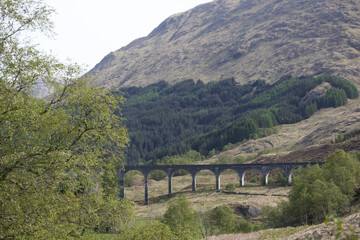 Naklejka premium Scenic view of a historic viaduct surrounded by green hills in Scotland during daytime