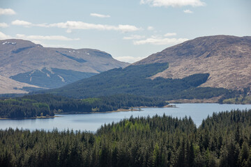 Majestic landscape of Loch Awe surrounded by rolling hills and dense forests in Scotland during a sunny day