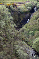 Obraz premium Waterfalls cascading through the lush green hills of Isle of Skye in Scotland during springtime
