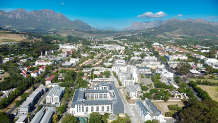 Aerial view of the town of Stellenbosch with campus building and accomodation in foreground and mountains in the background