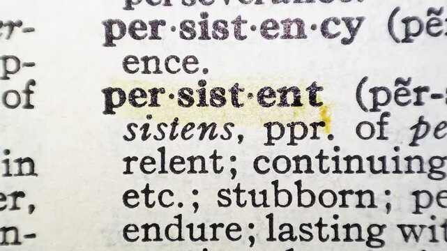 A man marks the definition from the word persistent on a printed page with a marker pen