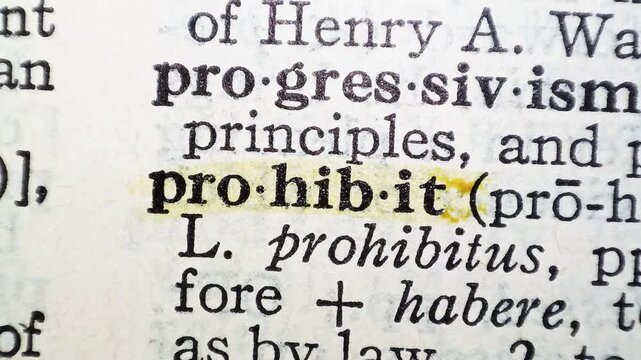 A man marks the definition from the word prohibit on a printed page with a marker pen