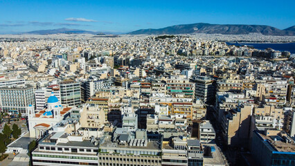 Imagem aérea da cidade de Atenas, com vista para templos milenares, edifícios modernos e a vibrante vida urbana grega em meio à herança da civilização helênica.