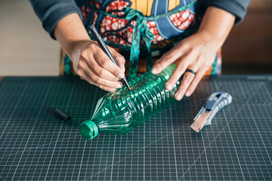 Designer drawing lines on plastic bottle for recycling project