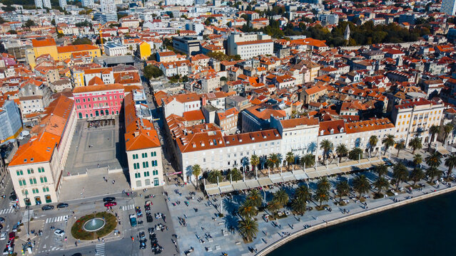 Fototapeta Drone registra a praça central de Split com suas construções históricas, ruas de pedra e pessoas circulando, em cenário costeiro vibrante e cultural