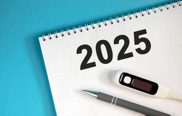 New year 2025 concept. Text on a notebook with a pen and a thermometer