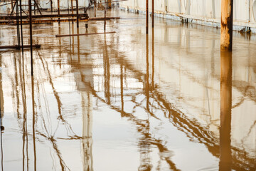 Fototapeta premium Flooded industrial area with reflected structures in brown water