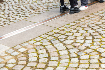 Close-up view of tourists standing between the Greenwich Prime Meridian marked by the brass strip on the ground in the courtyard of the Royal Observatory with markers of well known capital cities.