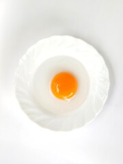 Duck egg yolk on a white plate on a white background.