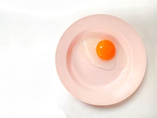 Duck egg yolk on a pink plate on a white background.