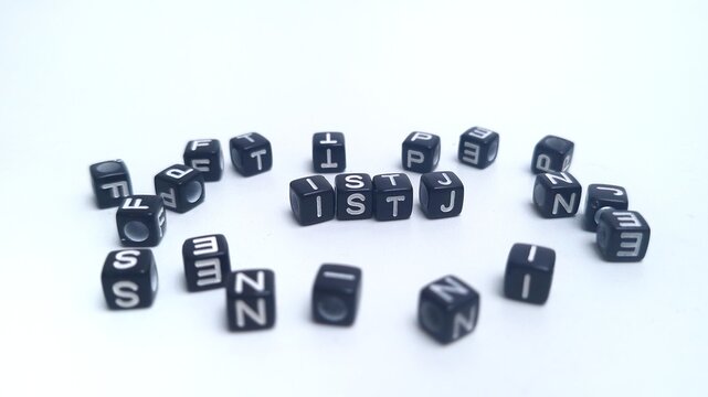 Scattered black plastic cubes, focus on the letters ISTJ in the center. The foreground and background are blurred. ISTJ is one of the 16 personality types identified by the MBTI test.