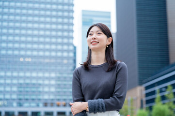 Fototapeta premium ビルを背景に笑顔の日本人女性