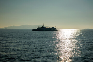 Fototapeta premium Boat sailing on the sea as the sun sets