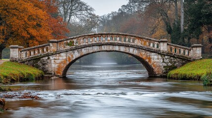 Fototapeta premium An old stone bridge over a calm river in an autumnal park.