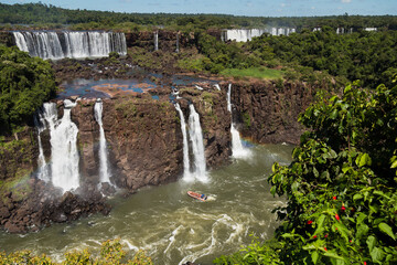 Obraz premium Spectacular top view of an extreme boat trip inside of the Iguazu Falls in Brazil. The waterfalls making a rainbow