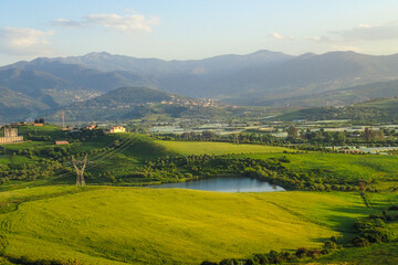 Naklejka premium African countryside, Spring day landscape of fields, meadows and hills with mountains in the background and blue sky with clouds, Algerian and a lake in the Algerian countryside, rural Jijel Algeria.