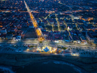 Aerial view of a coastal town at night, showcasing modern urban design.This aerial shot captures a coastal town at night, with illuminated streets, buildings, and a modern beachfront promenade. Karasu