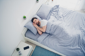 Top view photo of happy dreamy young man nightwear pajama lying bed indoors house apartment room