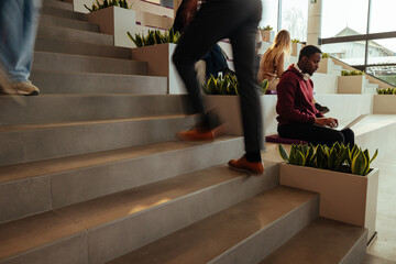 Businessman walking up stairs in modern office with people working and relaxing