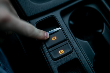 Car driver using fingers pushing electronic parking brake (EPB) in modern car for braking system
