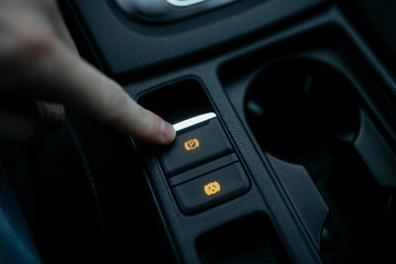 Car driver using fingers pushing electronic parking brake (EPB) in modern car for braking system