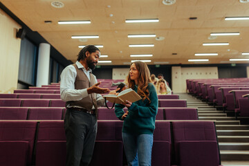 Professor and student discussing in university lecture hall