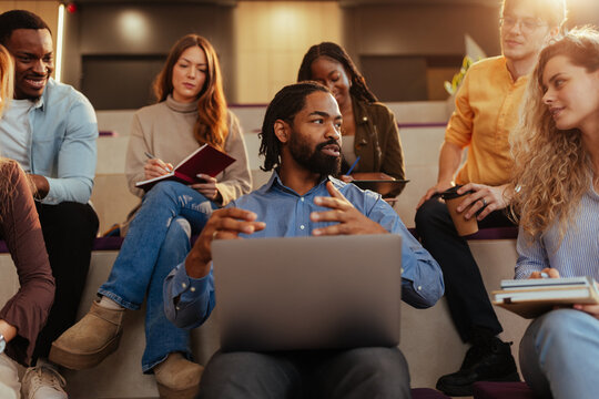 Professor leading discussion with university students using laptop