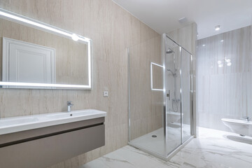Modern design of a spacious bathroom decorated in light beige tones. Shower behind a glass...