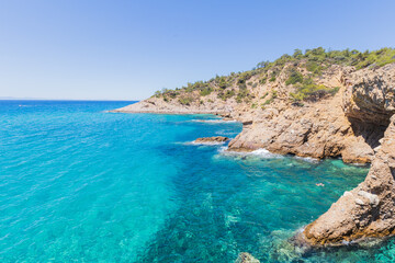 Obraz premium Crystal Clear Waters and Rocky Shoreline in Greece, Sunny Summer Day