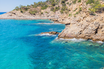 Crystal Clear Waters and Rocky Shoreline in Greece, Sunny Summer Day