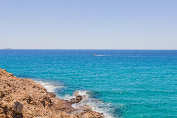 Tranquil scene of a rocky coastline meeting the crystal-clear turquoise waters of the Mediterranean Sea.