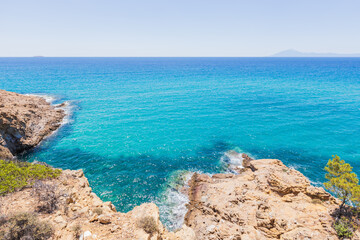 Crystal Clear Waters and Rocky Shoreline in Greece, Sunny Summer Day