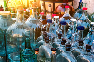 A variety of glass multi-colored bottles and jugs for pouring homemade wine.