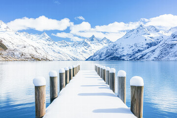 Naklejka premium Serene winter landscape with snow-capped mountains dock tranquil lake