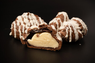Profiteroles with coconut cream on a black background.