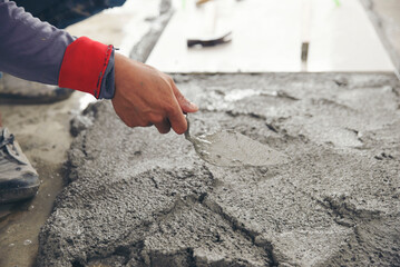 Builder man hand use trowel to leveling and plaster concrete cement wall at construction site