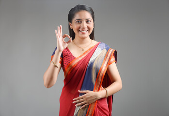 Traditional Indian Young woman in saree stands and making OK sign