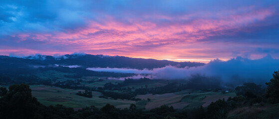 Sun rays illuminate colorful clouds at sunset in a scenic landscape