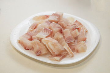 Pangasius fish fillet by pieces on the white plate. Fresh fish fillet.