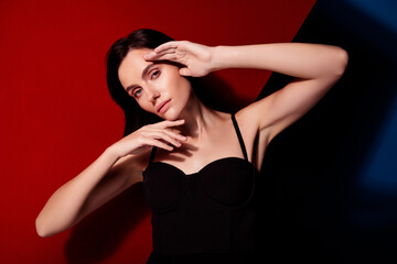 Elegant woman posing with artistic gesture against bold red and black background